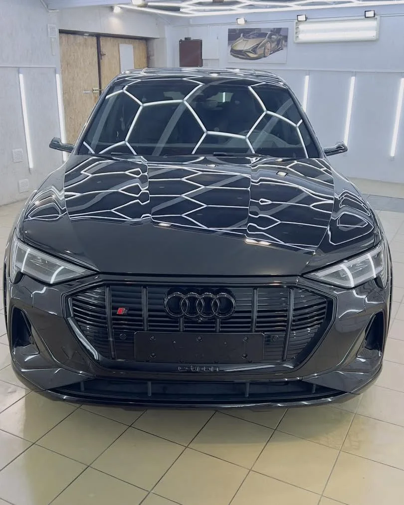 Juodas Audi e-tron po poliravimo — šešiakampio šviesos tinklo atspindys dangtyje